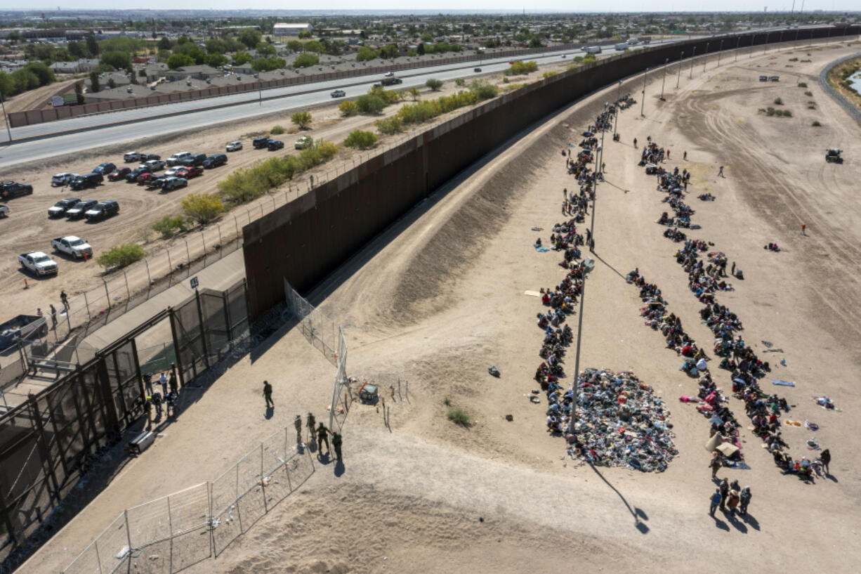 FILE - Migrants form lines outside the border fence waiting for transportation to a U.S. Border Patrol facility in El Paso, Texas, May 10, 2023. Washington&rsquo;s center of gravity on immigration has shifted demonstrably to the right. The debate is now focused on measures meant to keep migrants out as Republicans sense they have the political upper hand. A bipartisan group of senators tasked with finding a border deal this week is running out of time to reach an agreement.