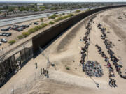 FILE - Migrants form lines outside the border fence waiting for transportation to a U.S. Border Patrol facility in El Paso, Texas, May 10, 2023. Washington&rsquo;s center of gravity on immigration has shifted demonstrably to the right. The debate is now focused on measures meant to keep migrants out as Republicans sense they have the political upper hand. A bipartisan group of senators tasked with finding a border deal this week is running out of time to reach an agreement.