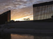 FILE - A pair of migrant families from Brazil passes through a gap in the border wall to reach the United States after crossing from Mexico in Yuma, Ariz., to seek asylum on June 10, 2021. A federal judge was poised Friday, Dec.8, 2023, to prohibit separation of families at the border for purposes of deterring immigration for eight years.