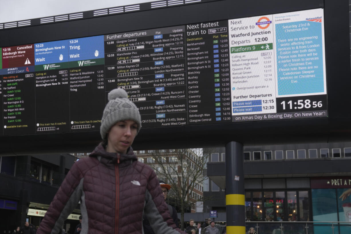 A traveller stands in front of an information display giving travel details for the upcoming Christmas holiday period at Euston Station in London, Thursday, Dec. 21, 2023. London Rail travellers over the Christmas holiday season will have to contend with disruptions to services due to engineering work and bad weather.
