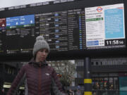 A traveller stands in front of an information display giving travel details for the upcoming Christmas holiday period at Euston Station in London, Thursday, Dec. 21, 2023. London Rail travellers over the Christmas holiday season will have to contend with disruptions to services due to engineering work and bad weather.