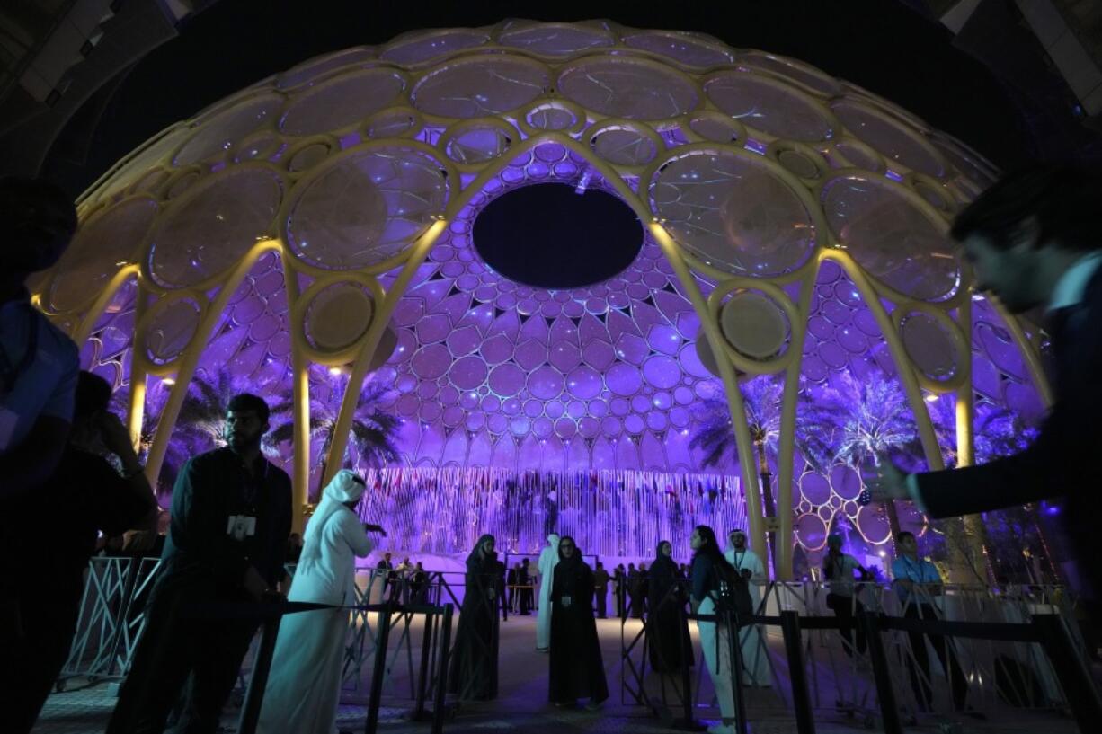 People walk near a lit up Al Wasl Dome at Expo City at the COP28 U.N. Climate Summit, Friday, Dec. 1, 2023, in Dubai, United Arab Emirates.