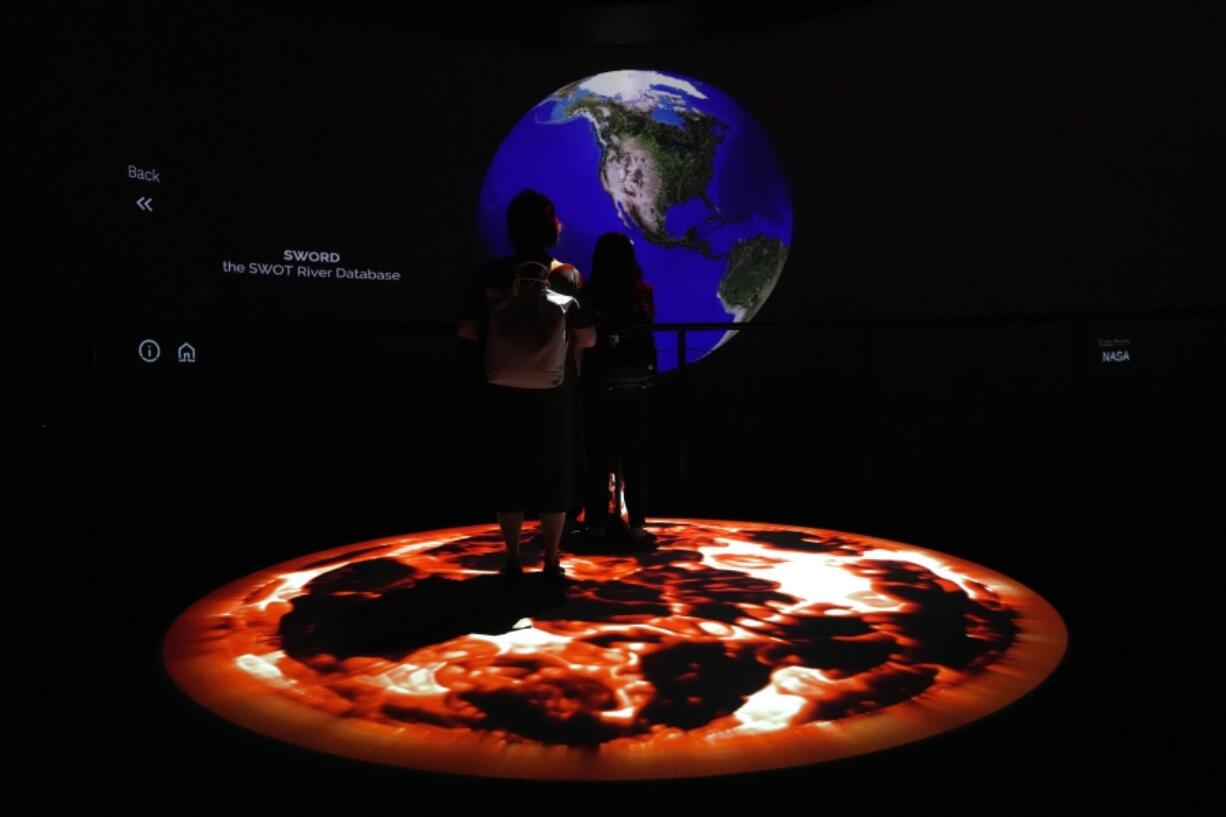 People look at artwork by Yiyun Kang at the COP28 U.N. Climate Summit, Sunday, Dec. 3, 2023, in Dubai, United Arab Emirates.