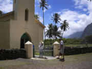 Kyong Son Toyofuku, left, her goddaughter Yunra Huh, center, and husband, Lance Toyofuku, right, walk into St. Philomena Church on July 18 during a tour of Kalaupapa, Hawaii. The church was expanded and used by St. Damien and his parishioners in the 1800s while he lived with and cared for leprosy patients banished to Kalaupapa.