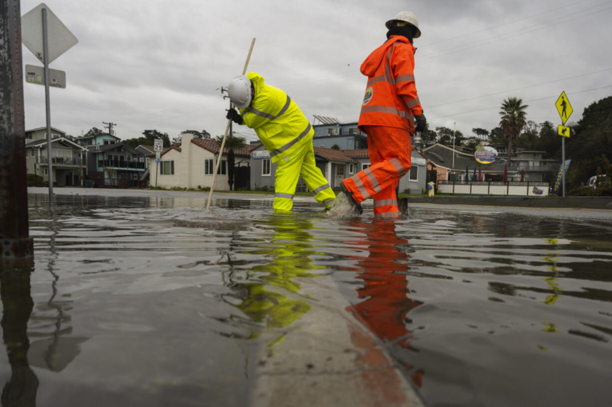 Santa Cruz County public works employees clear a storm drain in the Rio Del Mar neighborhood of Aptos, Calif., Wednesday, Dec.