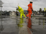 Santa Cruz County public works employees clear a storm drain in the Rio Del Mar neighborhood of Aptos, Calif., Wednesday, Dec.