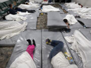 FILE - Women wait in a Border Patrol holding facility Friday, Dec. 15, 2023, in Tucson, Ariz.