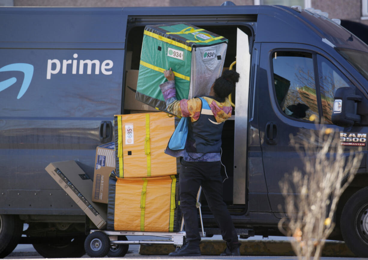 An Amazon Prime delivery person struggles with packages while making a stop at a high-rise apartment building on Tuesday, Nov. 28, 2023, in Denver.