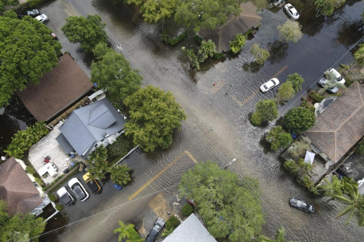 FILE - A pair of waterlogged cars sit abandoned in the road as floodwaters recede in the Sailboat Bend neighborhood of Fort Lauderdale, Fla., April 13, 2023. Flood risk and climate change are pushing millions of people to move from their homes, according to a new study by the risk analysis firm First Street Foundation.