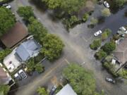 FILE - A pair of waterlogged cars sit abandoned in the road as floodwaters recede in the Sailboat Bend neighborhood of Fort Lauderdale, Fla., April 13, 2023. Flood risk and climate change are pushing millions of people to move from their homes, according to a new study by the risk analysis firm First Street Foundation.