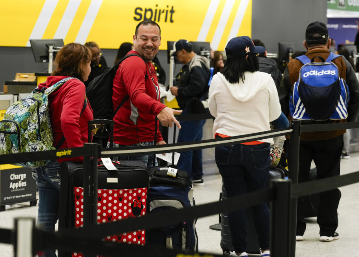 Travelers wait to check luggage into their Spirit Airlines at George Bush Intercontinental Airport, Tuesday, Nov. 21, 2023, in Houston.