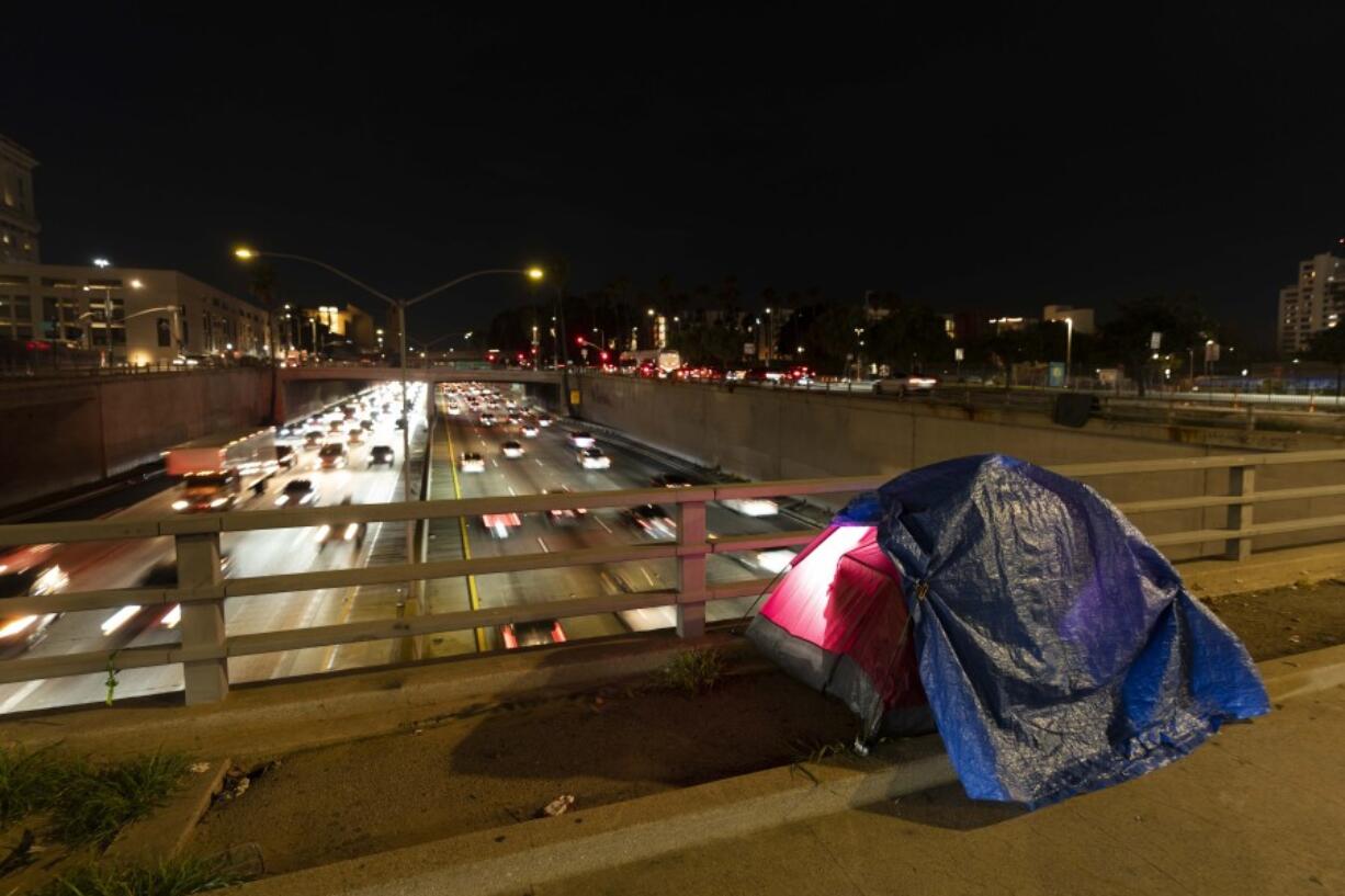 FILE - In this photo illuminated by an off-camera flash, a tarp covers a portion of a homeless person&rsquo;s tent on a bridge overlooking the 101 Freeway in Los Angeles, Thursday, Feb. 2, 2023. The United States experienced a dramatic 12 percent increase in homelessness as soaring rents and a decline in coronavirus pandemic assistance combined to put housing out of reach for more Americans, federal officials said Friday, Dec. 15, 2023. (AP Photo/Jae C.