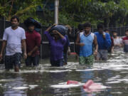 People wade through flood waters following heavy rains along the Bay of Bengal coast in Chennai, India, Tuesday, Dec.5, 2023. Tropical Storm Michaung began making landfall along India&rsquo;s southeastern coastline Tuesday, bringing with it torrential rains and strong winds.