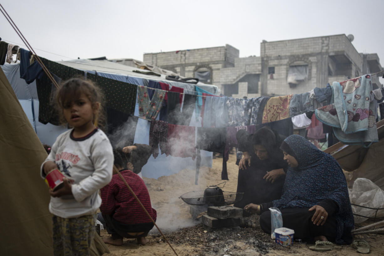 Palestinians displaced by the Israeli bombardment of the Gaza Strip cook at the makeshift tent camp in the Muwasi area on Thursday, Dec. 28, 2023.