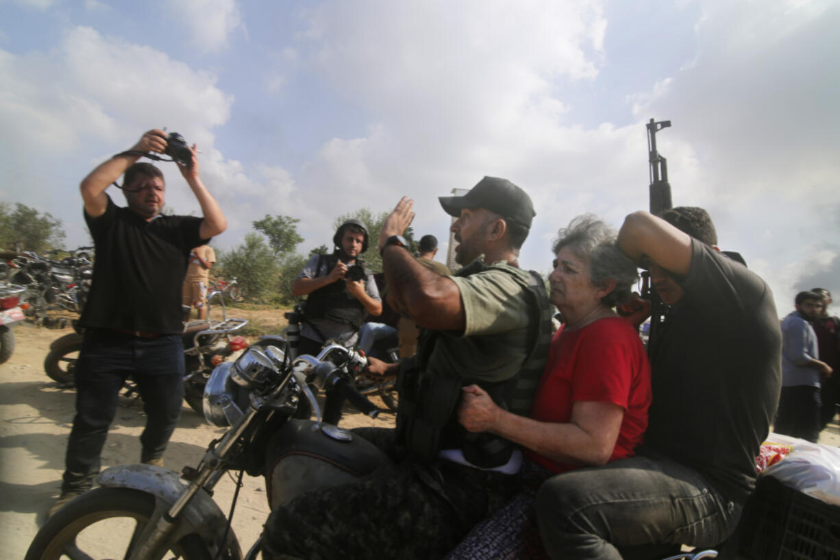 FILE - Palestinians transport a captured Israeli civilian, Adina Moshe, from her home in Kibbutz Nir Oz to the Gaza Strip on Oct. 7, 2023. An Associated Press review of hundreds of messages shared among Nir Oz residents, security camera footage and Hamas instruction manuals show the group planned ahead of time to target civilians, a change in tactic that heavily impacted how the war in Gaza played out.