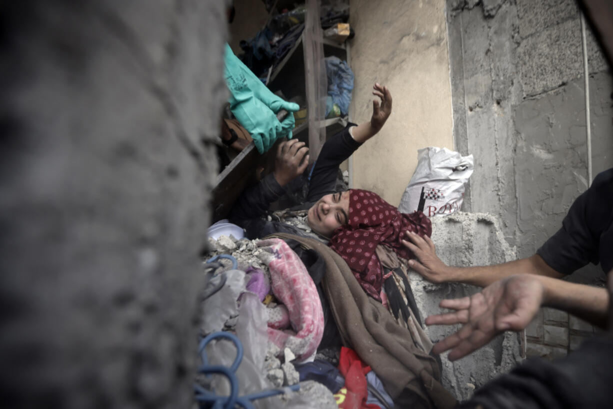 Palestinians try to rescue a woman stuck under the rubble of a destroyed building following Israeli airstrikes in Khan Younis refugee camp, southern Gaza Strip, Thursday, Dec. 7, 2023. In recent days, Israeli tanks have rumbled into southern Gaza, starting with Khan Younis.