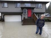 Bernie Crouse wades through water outside his home after the nearby South Fork Stillaguamish River crested early in the morning flooding several houses in this neighborhood, Dec. 5, 2023,  in the Arlington area of Seattle, Washington. Crouse got his dog Max out of the basement as it began flooding, after getting a call from another neighbor.