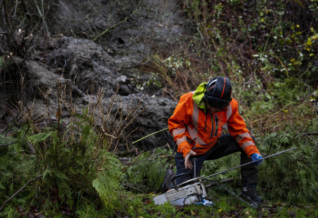 Seattle Parks and Recreation respond to a landslide Tuesday, Dec. 5, 2023, on Burke-Gilman Trail in Seattle. An atmospheric river is bringing heavy rain, flooding and warm winter temperatures to the Pacific Northwest. The National Weather Service on Tuesday issued a flood warning for parts of western Washington state.