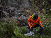 Seattle Parks and Recreation respond to a landslide Tuesday, Dec. 5, 2023, on Burke-Gilman Trail in Seattle. An atmospheric river is bringing heavy rain, flooding and warm winter temperatures to the Pacific Northwest. The National Weather Service on Tuesday issued a flood warning for parts of western Washington state.