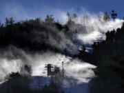 Man-made snow is blown from snowmaking equipment near the summit of Pleasant Mountain ski resort, Thursday, Dec. 21, 2023, in Bridgton, Maine. The New England ski industry is working to recover from a disastrous rain storm that washed away much of the snow just before the Christmas vacation season. (AP Photo/Robert F.