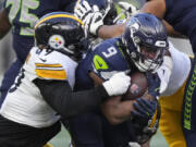 Seattle Seahawks running back Kenneth Walker III (9) is brought down by Pittsburgh Steelers defensive tackle Larry Ogunjobi (99) in the second half of an NFL football game Sunday, Dec. 31, 2023, in Seattle.