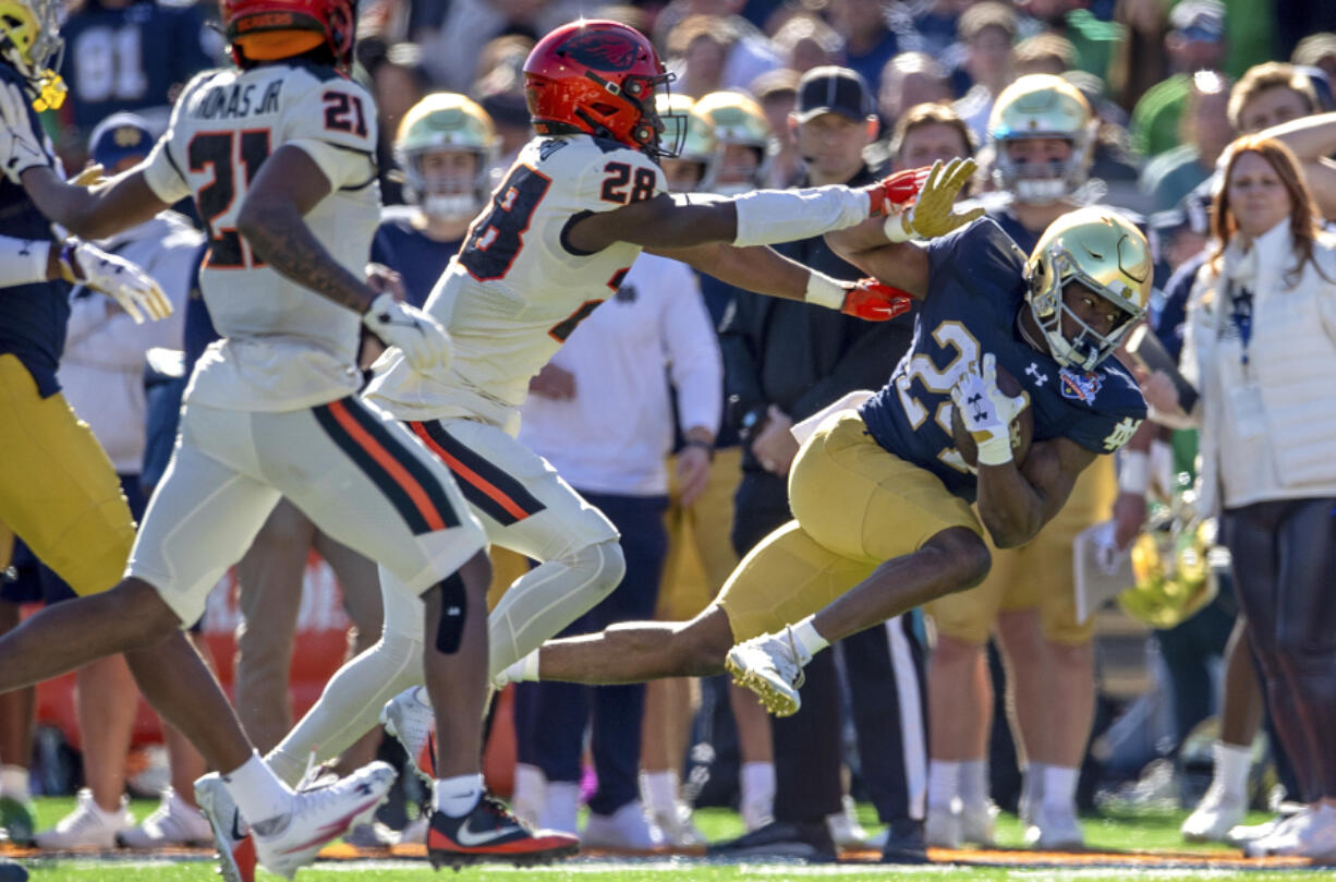 Notre Dame running back Jadarian Price (24) is tackled by Oregon State defensive back Kitan Oladapo (28) during the first half of the Sun Bowl NCAA college football game, Friday, Dec. 29, 2023, in El Paso, Texas.