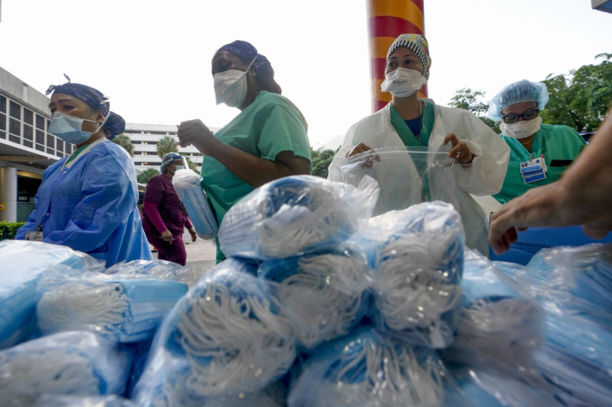 FILE - Healthcare workers line up for free personal protective equipment in front of murals by artist Romero Britto at Jackson Memorial Hospital, Tuesday, Sept. 22, 2020, in Miami.