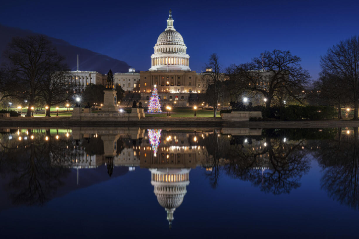 The U.S. Capitol building and the Capitol Christmas Tree are mirrored in the still waters of a reflecting pool early Christmas morning in Washington. (J.