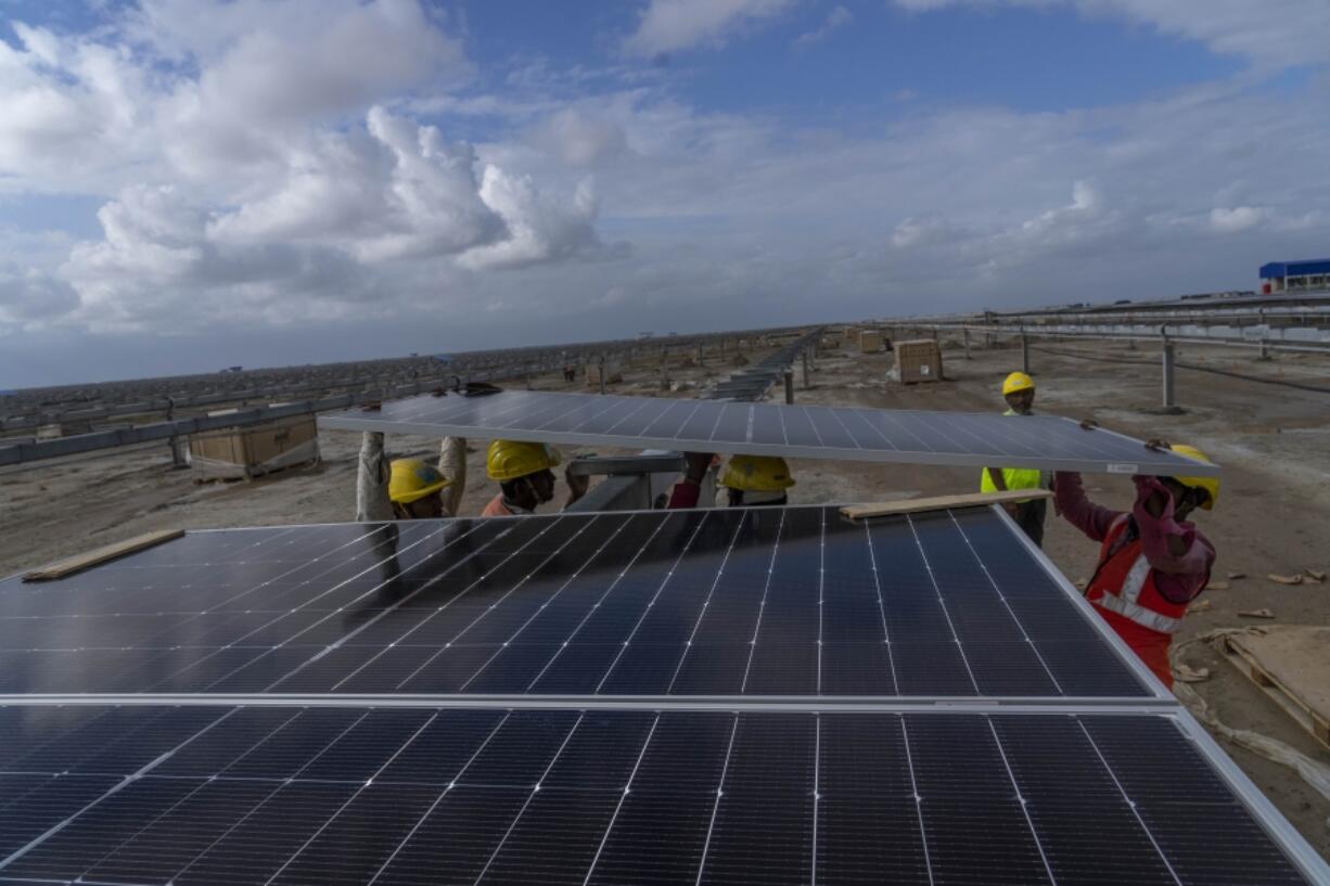 Workers install solar panels Sept. 21 at the under construction Adani Green Energy Limited&rsquo;s Renewable Energy Park in the salt desert of Karim Shahi village, near Khavda, Bhuj district near the India-Pakistan border in the western state of Gujarat, India. Led by new solar power, the world added renewable energy at breakneck speed in 2023, in an effort to turn away from fossil fuels to stave off severe Earth warming and its effects.