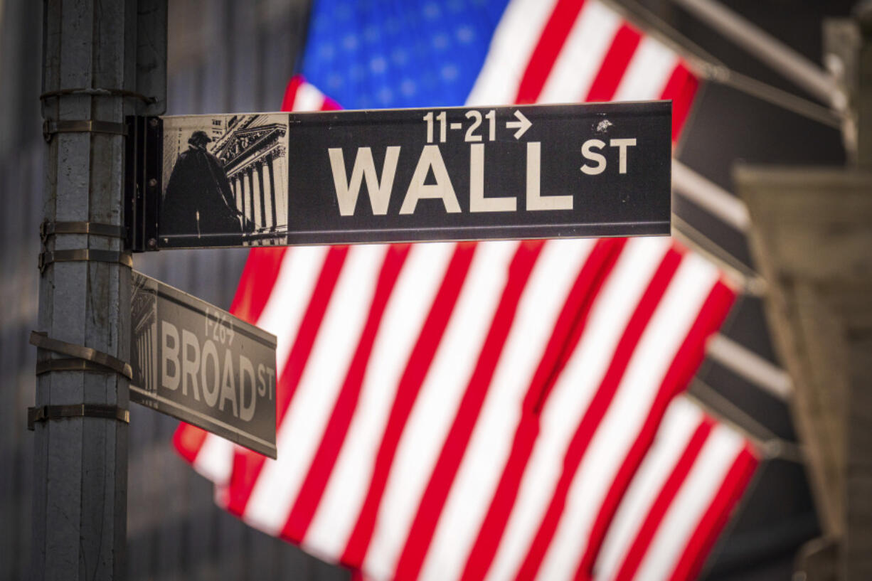 File - The sun shines through American flags flying in front of the New York Stock Exchange at the corner of Wall and Broad Streets in New York City on Nov. 14, 2023. Inflation has cooled enough to get investors looking ahead to a 2024 where interest rates may be on the way down instead of up. (AP Photo/J.