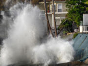 Waves smash against a sea wall next to homes along the California coast in Malibu Beach, Calif., on Friday. Back-to-back storms off the Pacific Ocean will bring rain and snow to Southern California this week, along with the potential for another round of big waves.