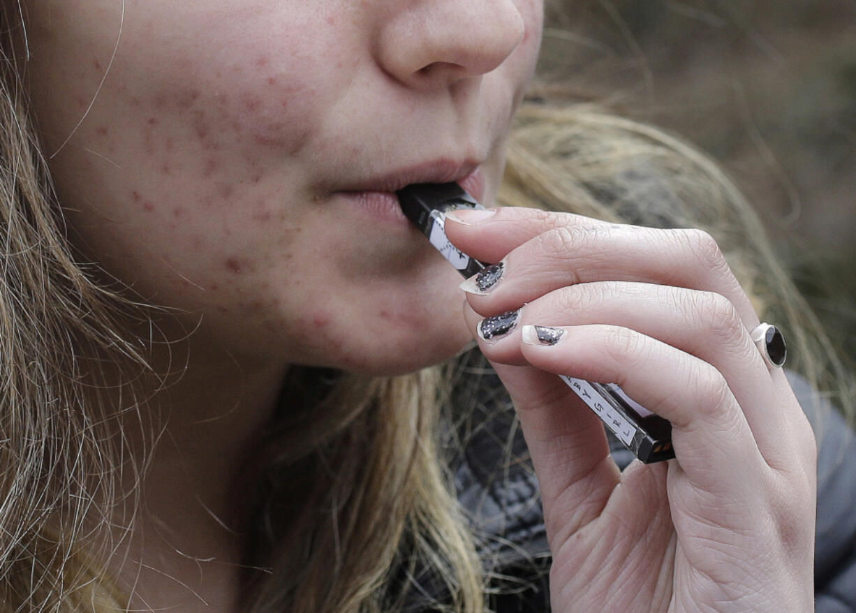 A high school student uses a vaping device near a school campus in Cambridge, Mass., on April 11, 2018.