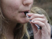 A high school student uses a vaping device near a school campus in Cambridge, Mass., on April 11, 2018.