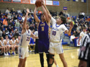 Columbia River’s John Reeder goes up for a shot attempt against Ridgefield’s Drew Krsul (23) and Colten Castro (10) during a 2A GSHL boys basketball game on Thursday, Jan. 4, 2024, at Ridgefield High School.