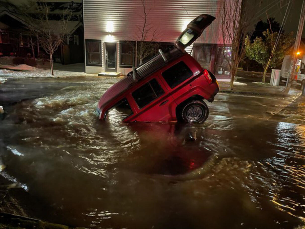 A vehicle is partially submerged in a sinkhole that opened up at West 30th and Washington streets in Vancouver early Saturday morning.