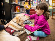 Noemie Leibov, 8, pauses reading aloud to pet Strummer during Tails and Tales at the Mukilteo Library on Jan. 17 in Mukilteo.