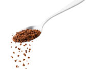 Instant coffee spills from a spoon.