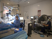 Dr. William Herzig, left, works with Dr. Jacob Calvert as they use the da Vinci robotic surgery system to perform a hysterectomy Wednesday morning on patient Tina Sixberry at Vancouver Clinic Salmon Creek. The facility is the first stand-alone outpatient surgical center in the region to use this system.