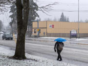 A pedestrian takes shelter under an umbrella as freezing rain transitions to all rain as the temperature rises Wednesday morning, Jan. 17, 2024.