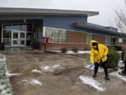 Custodian Mason Rivera of Crestline Elementary School clears ice from the front walkway following a period of winter weather Thursday morning in east Vancouver. The school was closed again for classes Thursday due to a chance of freezing rain in the forecast.
