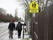 Pedestrians walk carefully along an icy sidewalk near Wy'East Middle School on Thursday morning, Jan. 18, 2024.