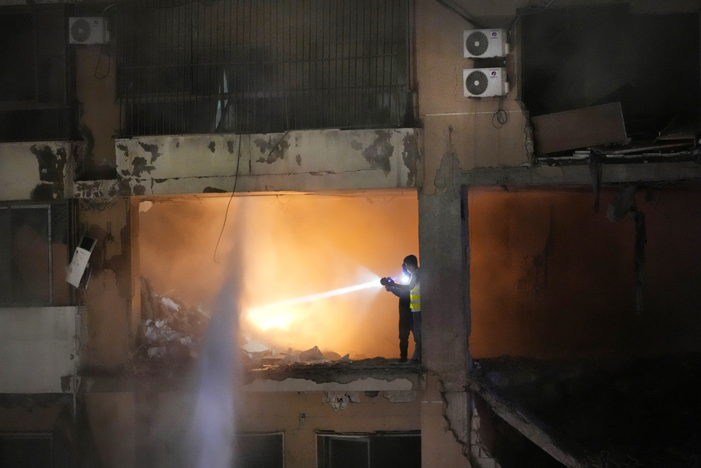 Civil defense workers search for survivors inside an apartment following a massive explosion in the southern suburb of Beirut, Lebanon, Tuesday, Jan. 2, 2024.