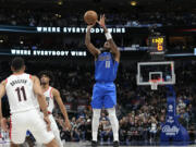 Dallas Mavericks guard Kyrie Irving, right, pulls up for a jump shot against Portland Trail Blazers defenders Malcolm Brogdon, left, and Shaedon Sharpe, center, during the first half of an NBA basketball game in Dallas, Friday, Jan. 5, 2024.
