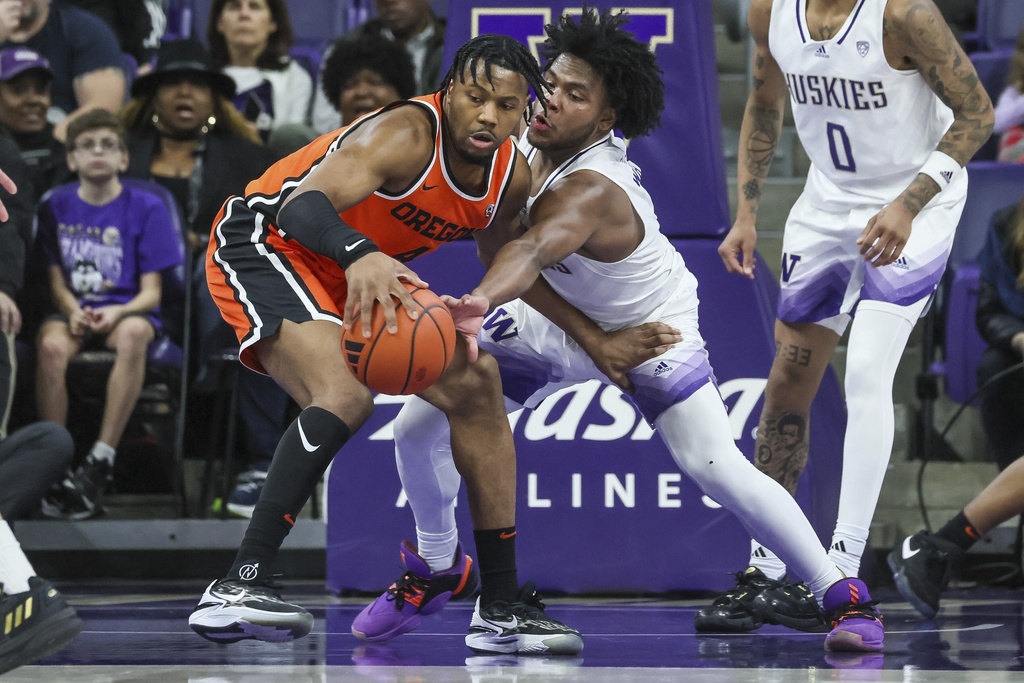 Oregon State guard Dexter Akanno, left, fends off Washington Huskies guard Sahvir Wheeler during the first half of an NCAA college basketball game Saturday, Jan. 6, 2024, in Seattle.