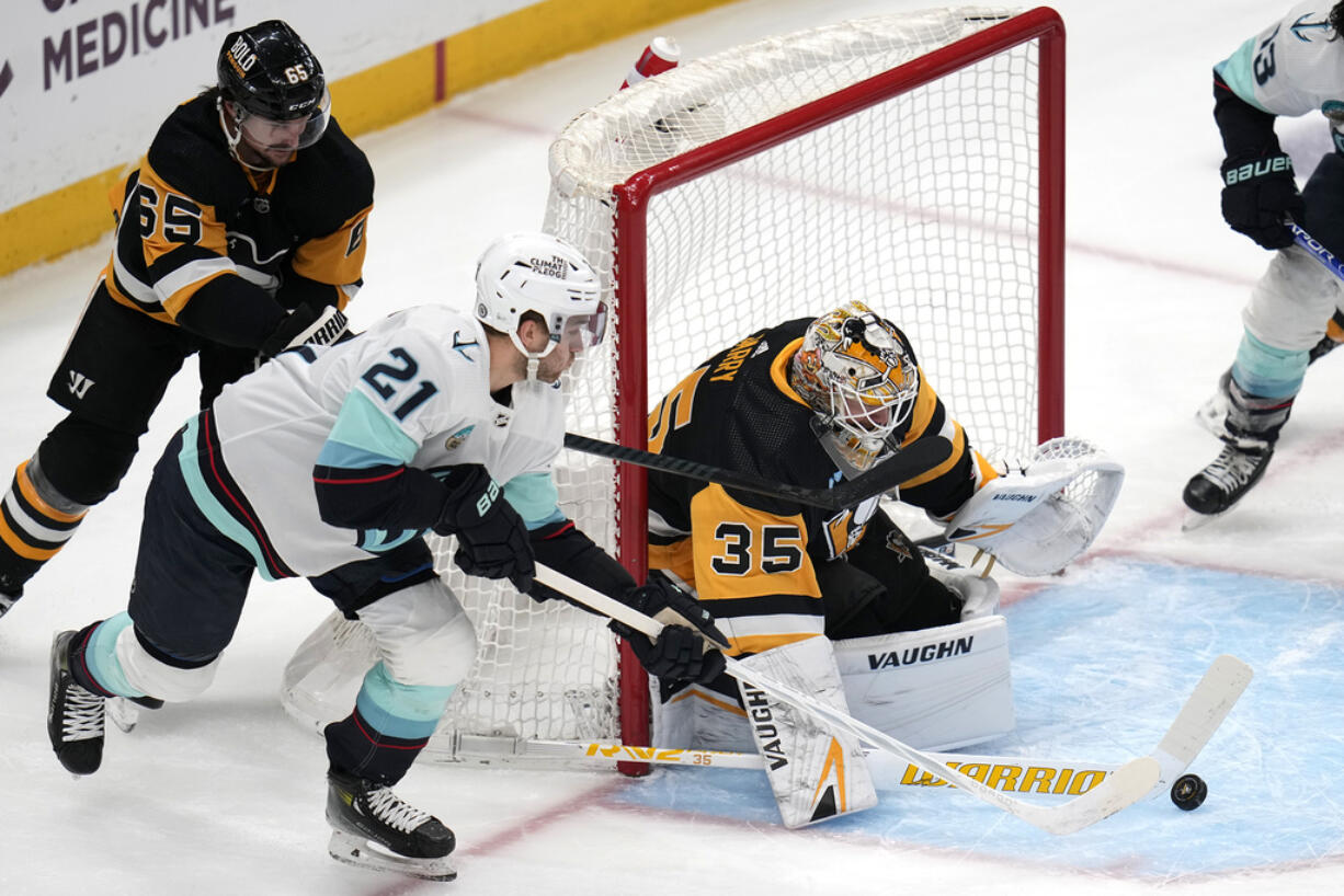 Pittsburgh Penguins goaltender Tristan Jarry (35) blocks a shot attempt by Seattle Kraken's Alex Wennberg (21) with Erik Karlsson (65) defending during the first period of an NHL hockey game in Pittsburgh, Monday, Jan. 15, 2024. (AP Photo/Gene J.