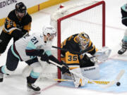 Pittsburgh Penguins goaltender Tristan Jarry (35) blocks a shot attempt by Seattle Kraken's Alex Wennberg (21) with Erik Karlsson (65) defending during the first period of an NHL hockey game in Pittsburgh, Monday, Jan. 15, 2024. (AP Photo/Gene J.