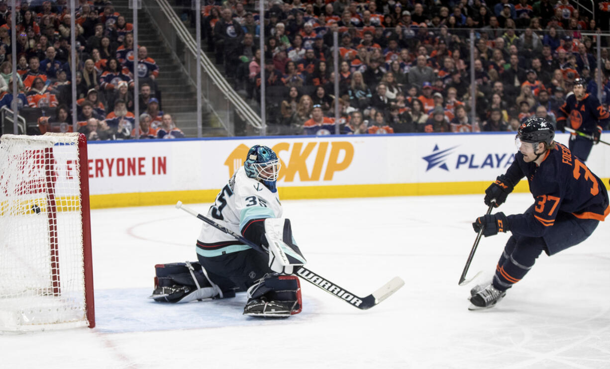 Seattle Kraken goalie Joey Daccord (35) is scored against by Edmonton Oilers' Warren Foegele (37) during second-period NHL hockey game action in Edmonton, Alberta, Thursday, Jan. 18, 2024.