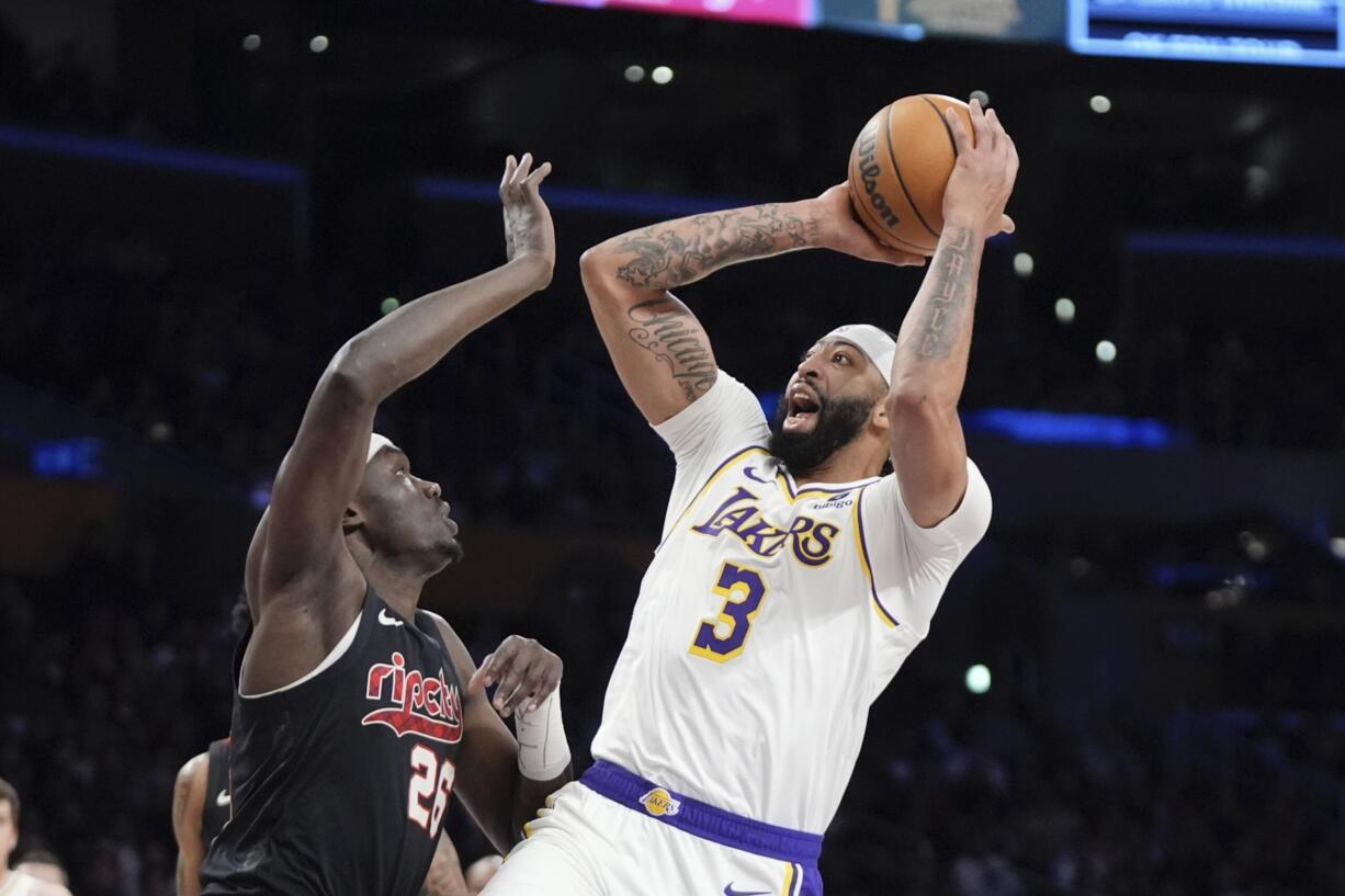 Los Angeles Lakers forward Anthony Davis, right, shoots as Portland Trail Blazers center Duop Reath defends during the first half of an NBA basketball game Sunday, Jan. 21, 2024, in Los Angeles. (AP Photo/Mark J.