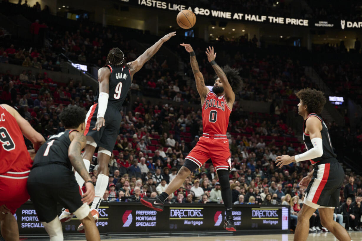 Chicago Bulls guard Coby White, right, shoots a jump shot against Portland Trail Blazers forward Jerami Grant, left, during the first half of an NBA basketball game in Portland, Ore., Sunday, Jan. 28, 2024.