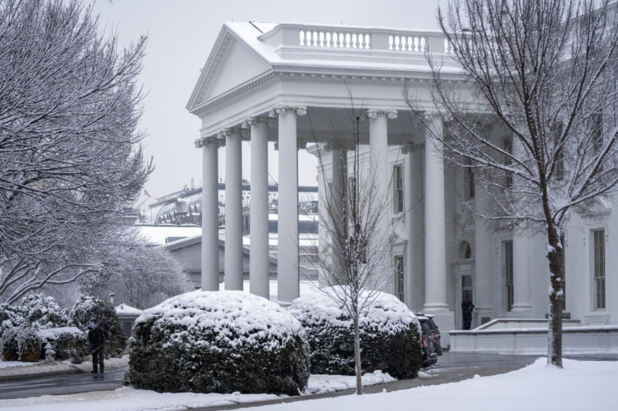 A worker removes snow from the White House driveway during a winter storm, Friday, Jan. 19, 2024, in Washington.